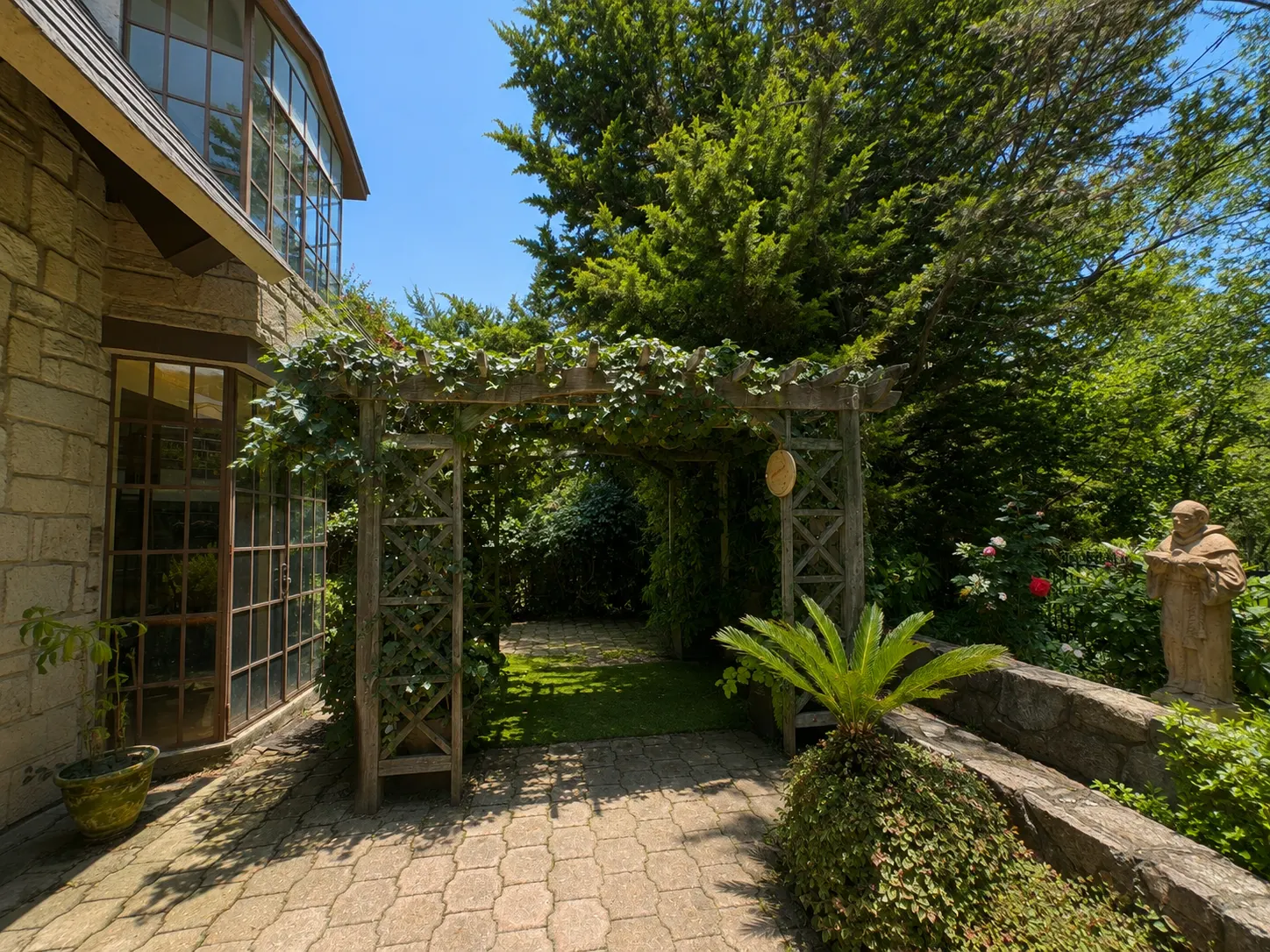Terraza — Pérgola cubierta de vegetación, entre el patio de piedra y el jardín.